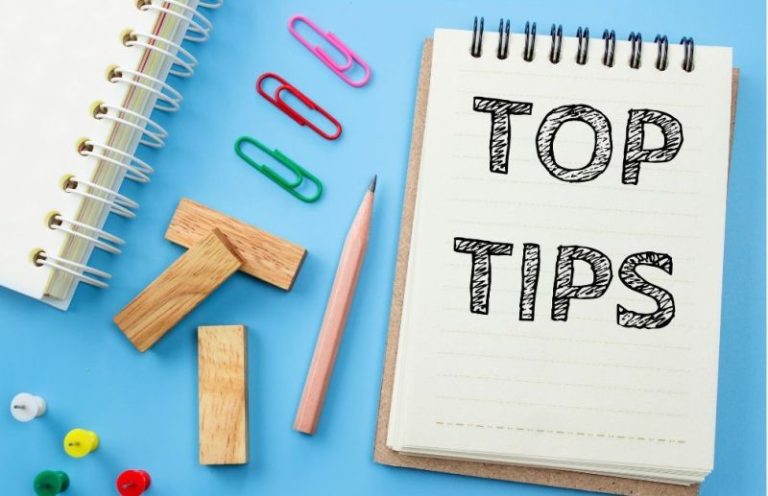 a notebook showing "Top Tips Text" with pencil and paper clips and a pencil on a blue surface